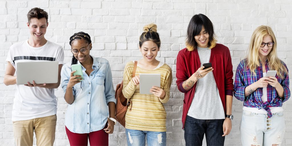 diverse young people smiling at electronic devices